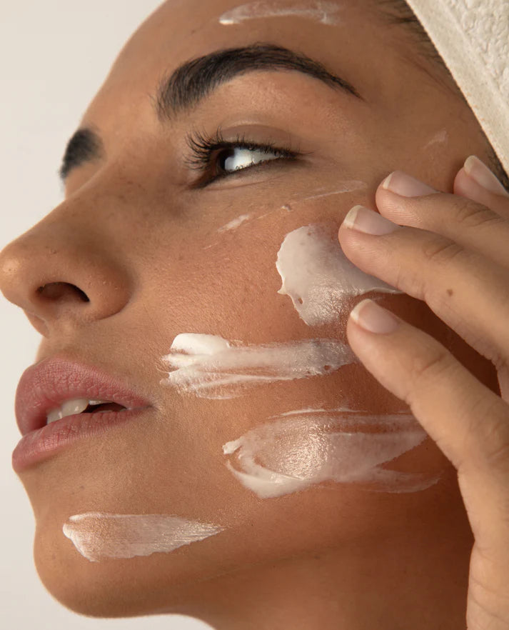 Woman applying cream to her face with a neutral background | Makari de Suisse Uganda